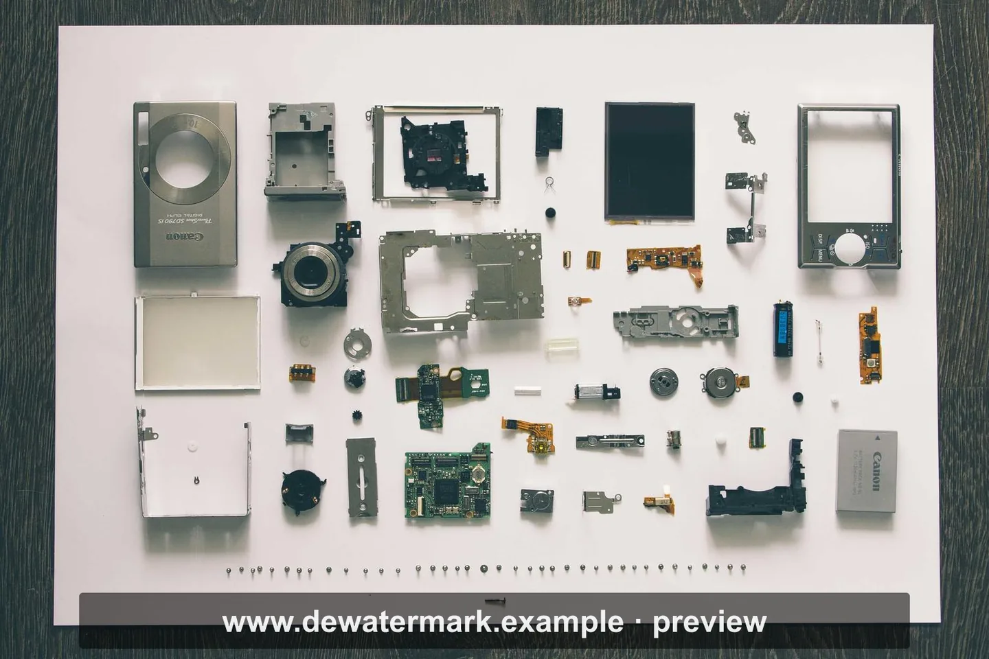 Overhead photograph of a disassembled camera laid out in rows, with a preview bar across the bottom
