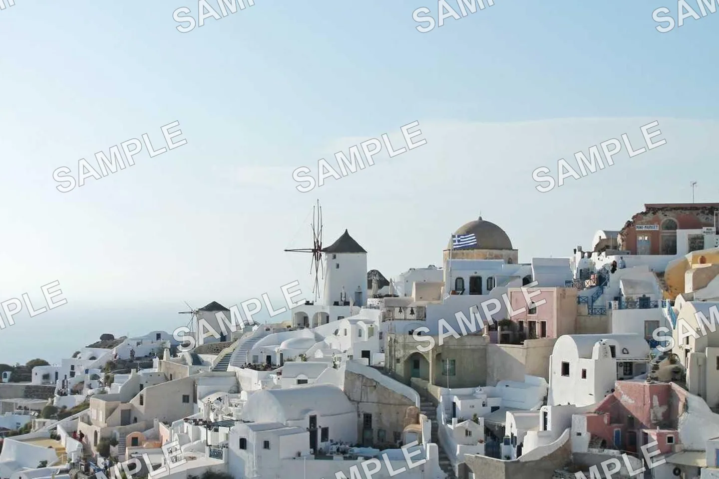 Photograph of a whitewashed hillside town and windmill under a repeating SAMPLE grid